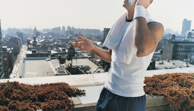 Businessman Wearing Sportswear Standing Outdoors on a Balcony Talking on His Mobile Phone