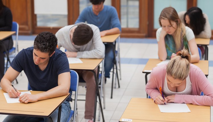 Students taking the ACT test at desks in a highschool.
