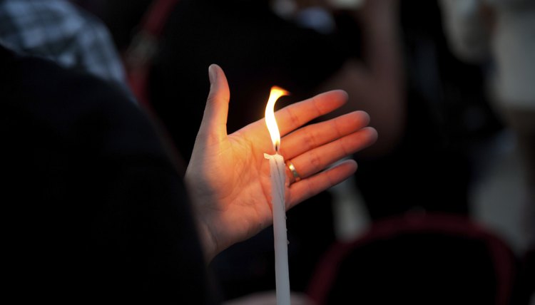A woman holds a candle at a religious vigil.