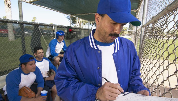 Sports Coach Writing on a Clipboard in a Dugout and Team Watching