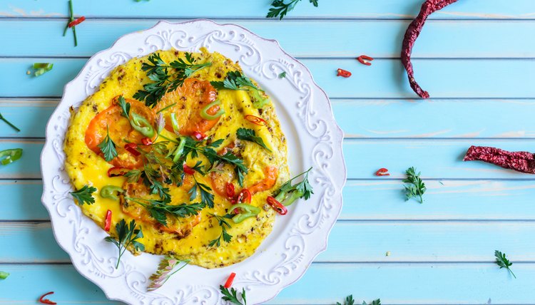 Omelette with tomatoes, chili on plate over wooden turquoise background