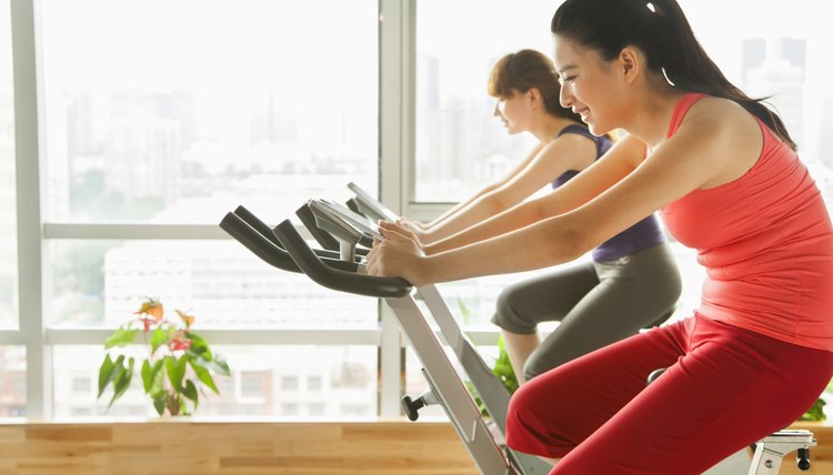 Young women on stationary bikes exercising in the gym
