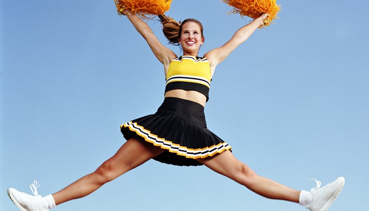 Cheerleader jumping with pompoms in mid air
