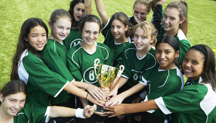 Girls (12-15) football team holding trophy, smiling, elevated view