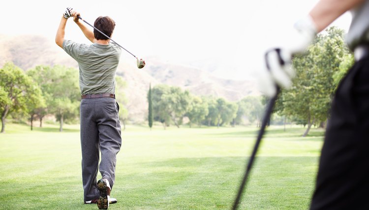 Two men playing golf, one standing in foreground