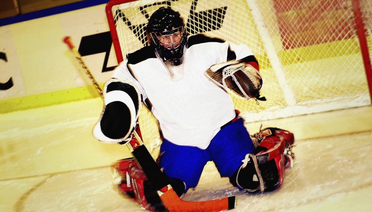 Portrait of ice hockey player kneeling on ice in front of goal, tilt