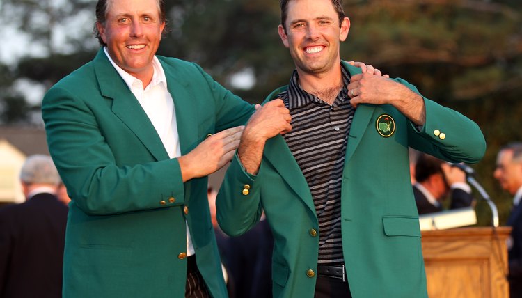 Past champion Phil Mickelson, left, presents 2011 Masters winner Charl Schwartzel with the tournament's trademark green jacket.