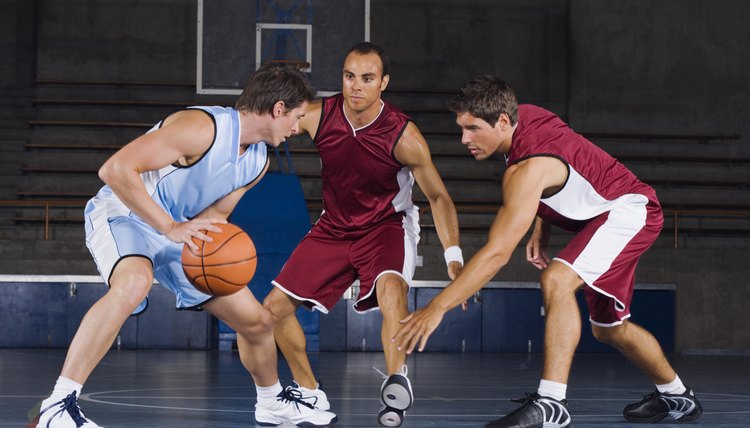 Man dribbling basketball against defenders