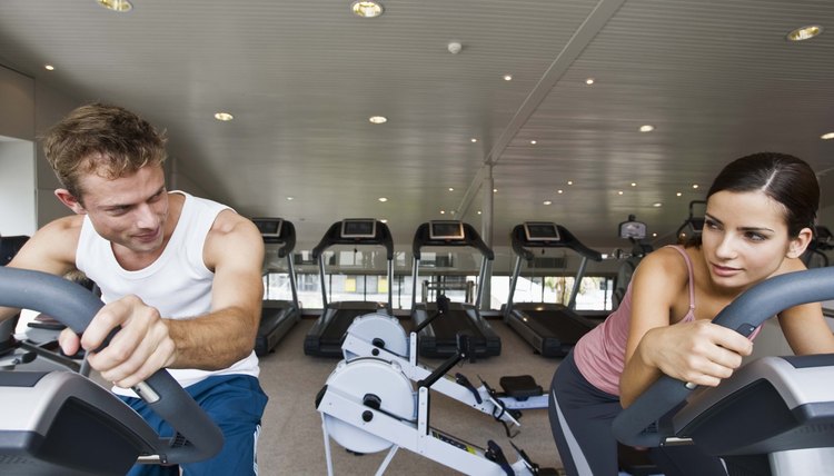 Man watching woman on exercise bike at gym