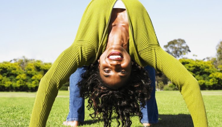 African woman doing back bend in grass