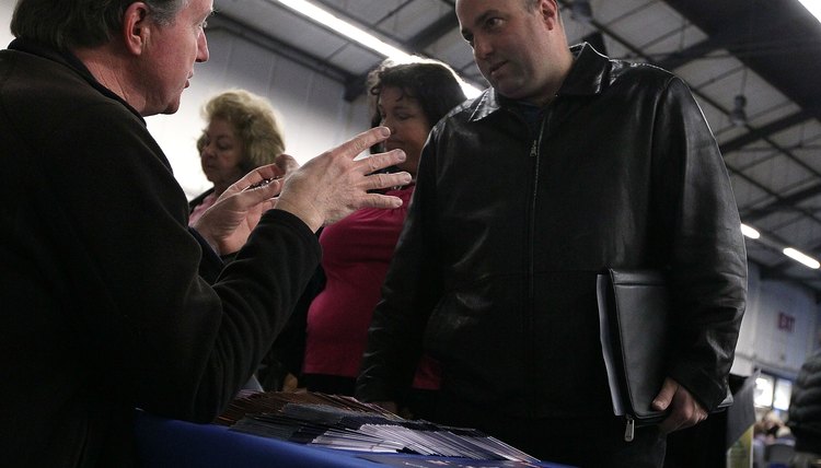 A soldier talks with a military recruiter at a table.