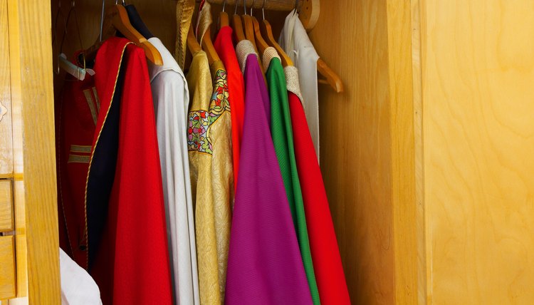 Various clergy robes hang in a closet.
