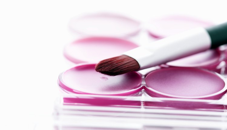 A makeup brush on top of a pink palette.