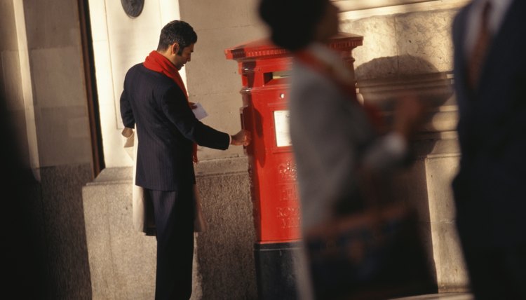 Businessman mailing letter at post box in street