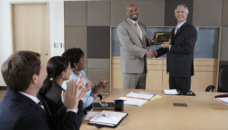 Executives applauding for man receiving 'Employee of the Month' plaque
