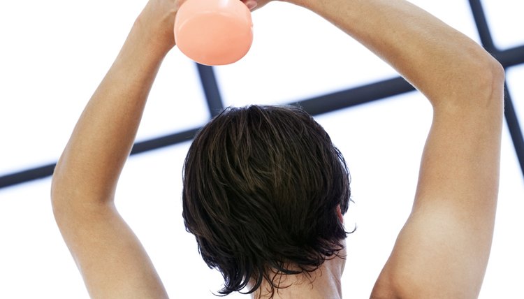 man clutching a dumbbell over his head