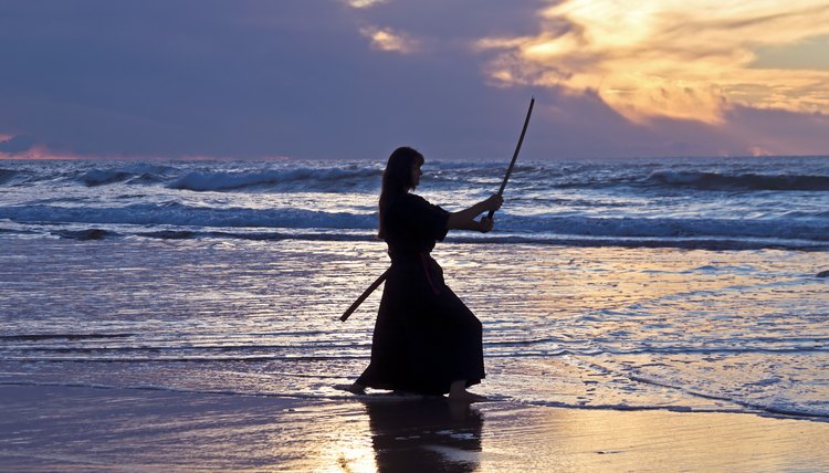 Young samurai women with Japanese sword(Katana) at sunset on the