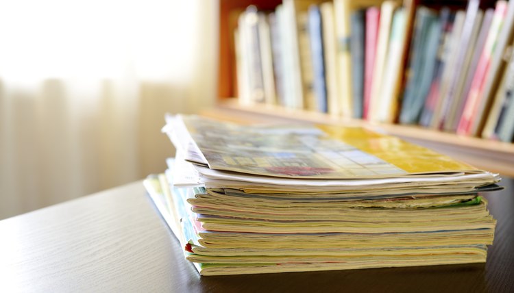 A collection of old magazines on a table near a bookshelf.