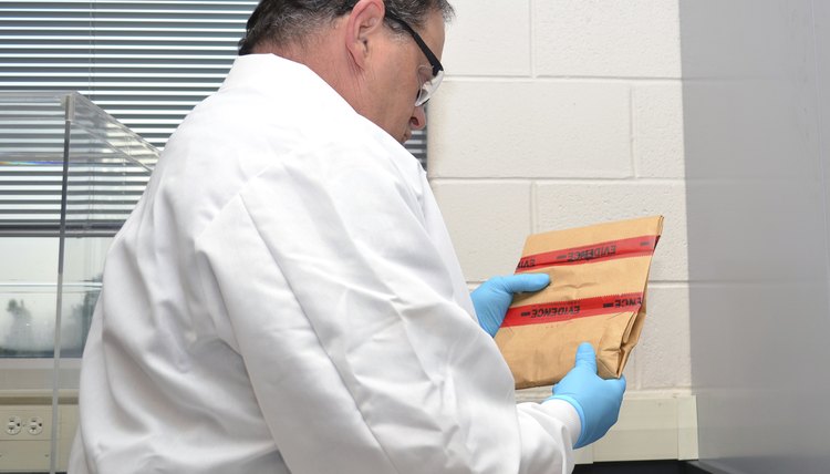 A forensics scientist holds an envelope containing evidence from a crime scene.