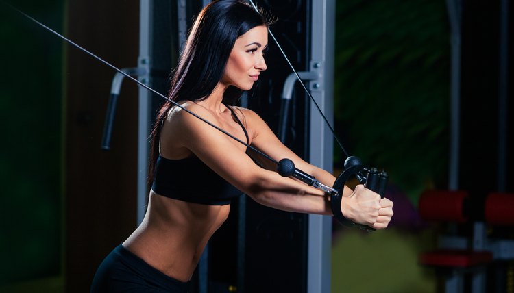 young fitness woman execute exercise with exercise-machine Cable Crossover in gym, horizontal photo.