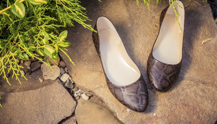 A pair of snakeskin ballet flat shoes on a rock.