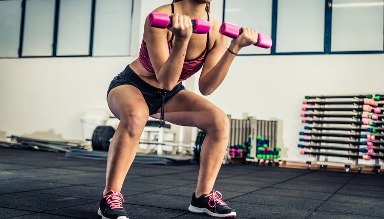 Athletic young woman doing squat exercises for the buttocks - Fitness model working out in a gym - Pretty young woman training to stay fit and healthy