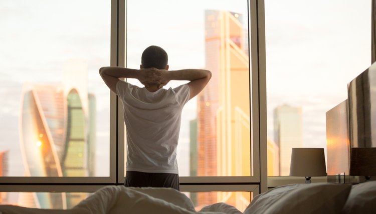 Young man watching sunrise in his bedroom