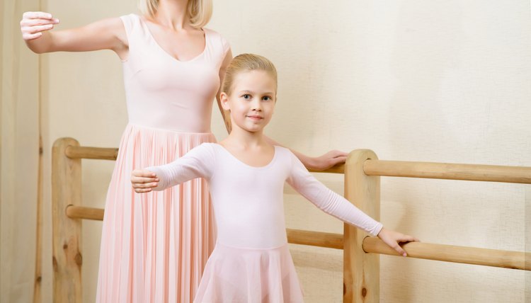 Ballet teacher and her apprentice are holding a pose