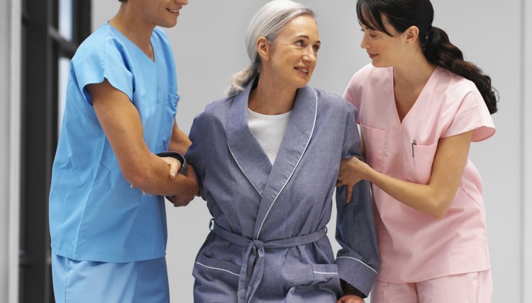 Close-up of mid adult doctor and young nurse helping mature woman out of wheelchair