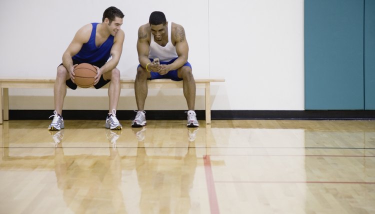 Two men sitting on sidelines of basketball court