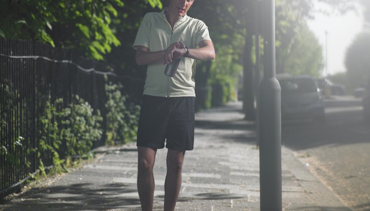 Mid adult man standing at street, looking at watch