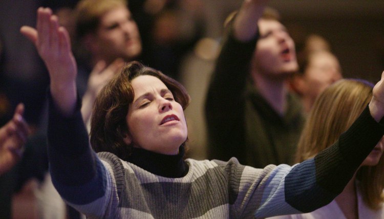 Woman singing worship music wit her arms lifted.