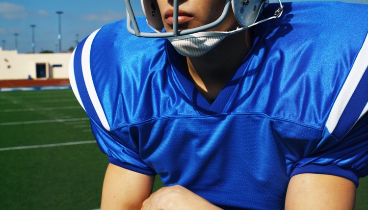 American football player (16-20) holding football looking into the distance