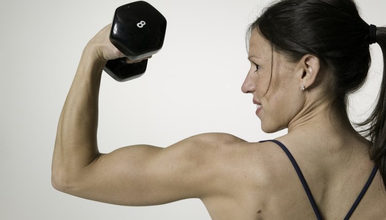 Woman weight lifting, posing in studio, portrait