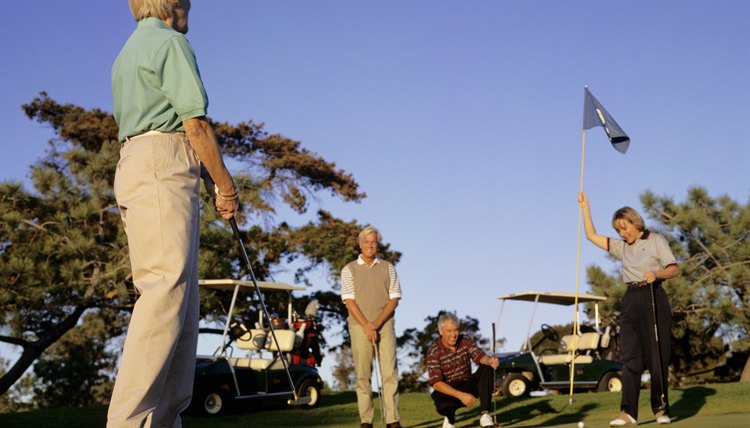 Four people on putting green at golf course