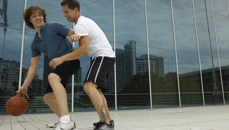 Two young men playing basketball outside office, smiling