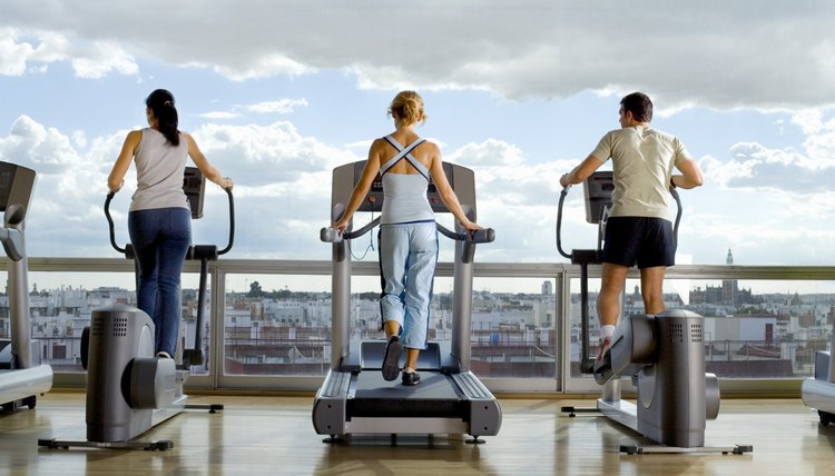 Rear view of People using exercise equipment in front of a window