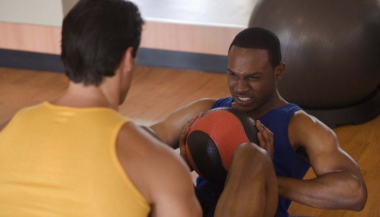 Personal trainer holding feet of man doing sit-ups