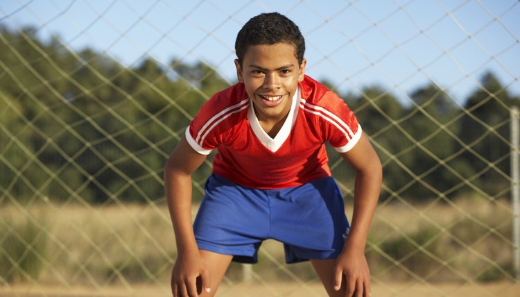 Portrait of goalie boy (12-13) standing in goal post, smiling