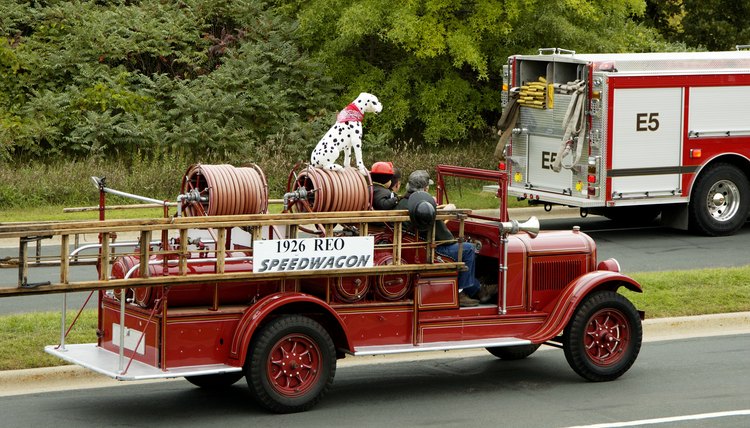 A Dalmatian sits on top of a fire engine.
