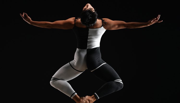Male ballet dancer in mid air pose, arms extended, rear view