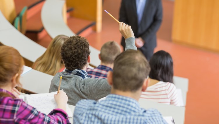 Student raising hand in lecture hall.
