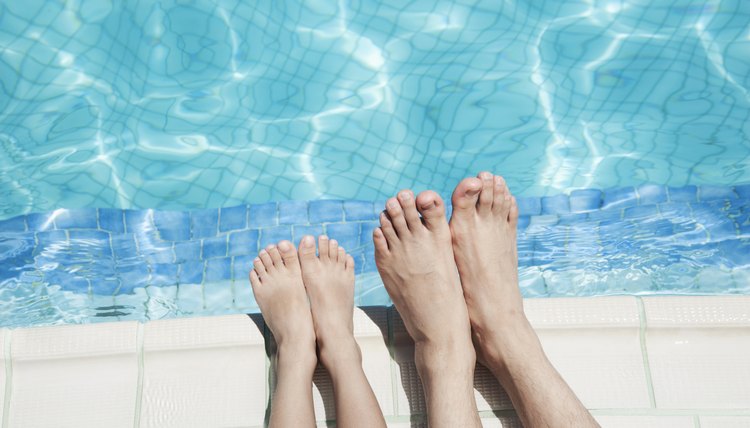 Close up of two people's legs by the pool side