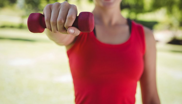 Fit woman lifting dumbbell in park