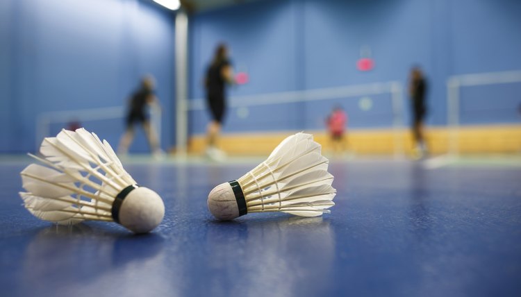 badminton courts with players competing; shuttlecocks in the foreground