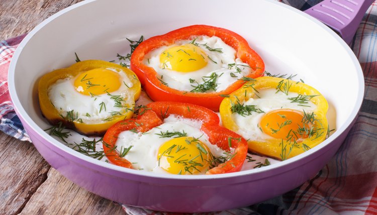 fried eggs with yellow and red peppers in pan horizontal