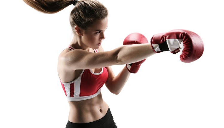 Boxer woman during boxing exercise making direct hit with glove