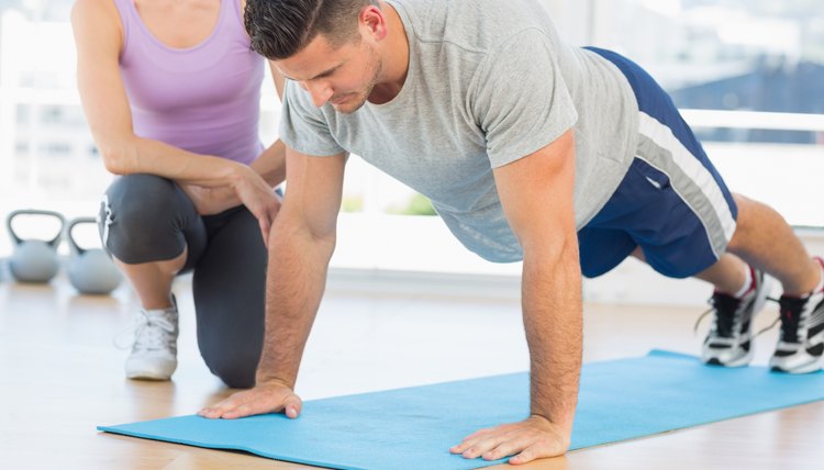 Trainer assisting man with push ups