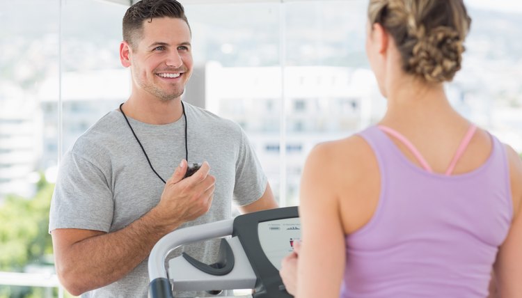 Trainer helping woman on treadmill