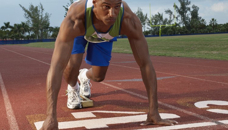 Male athlete at starting blocks on race track